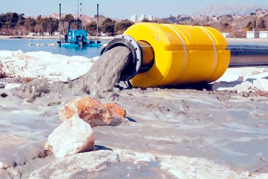 Dredge pipeline discharging sand for coastal reclamation, with the dredge offshore